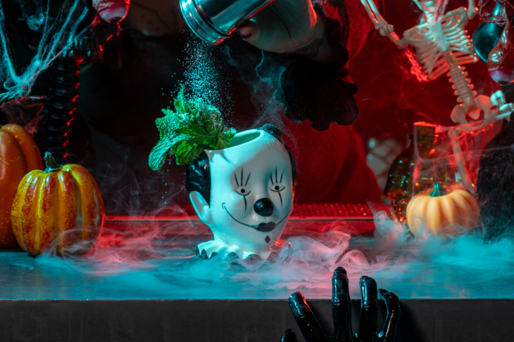 A mug shaped like a clown's head, surrounded by Halloween decorations