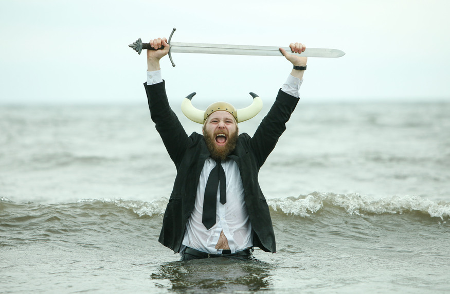A man in the sea wearing a suit holding a sword above his head