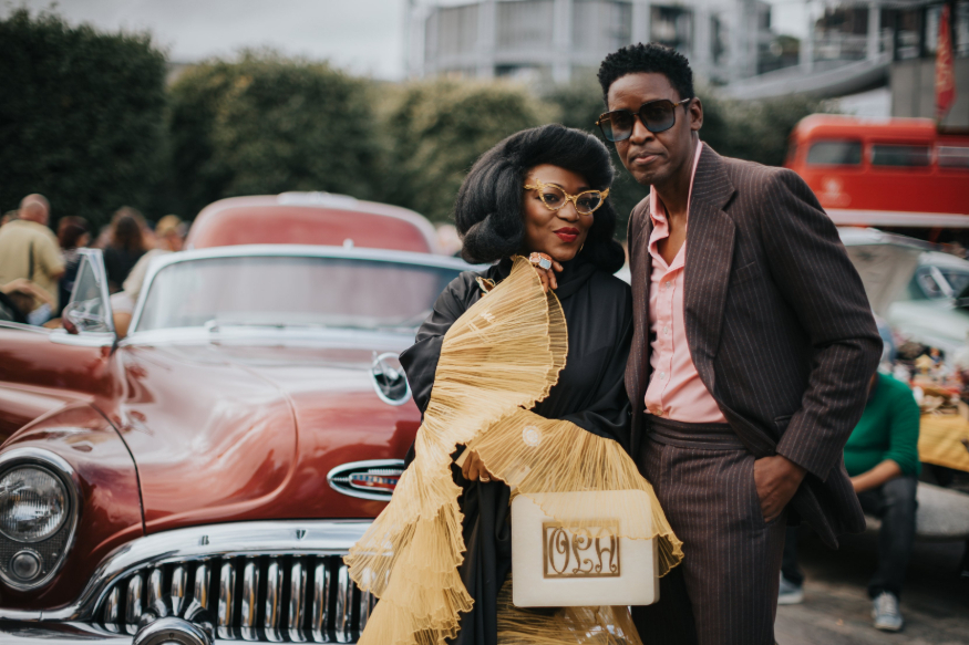 Things to do in London this weekend: a fashionable couple posing for a photo in front of a burgundy coloured classic car