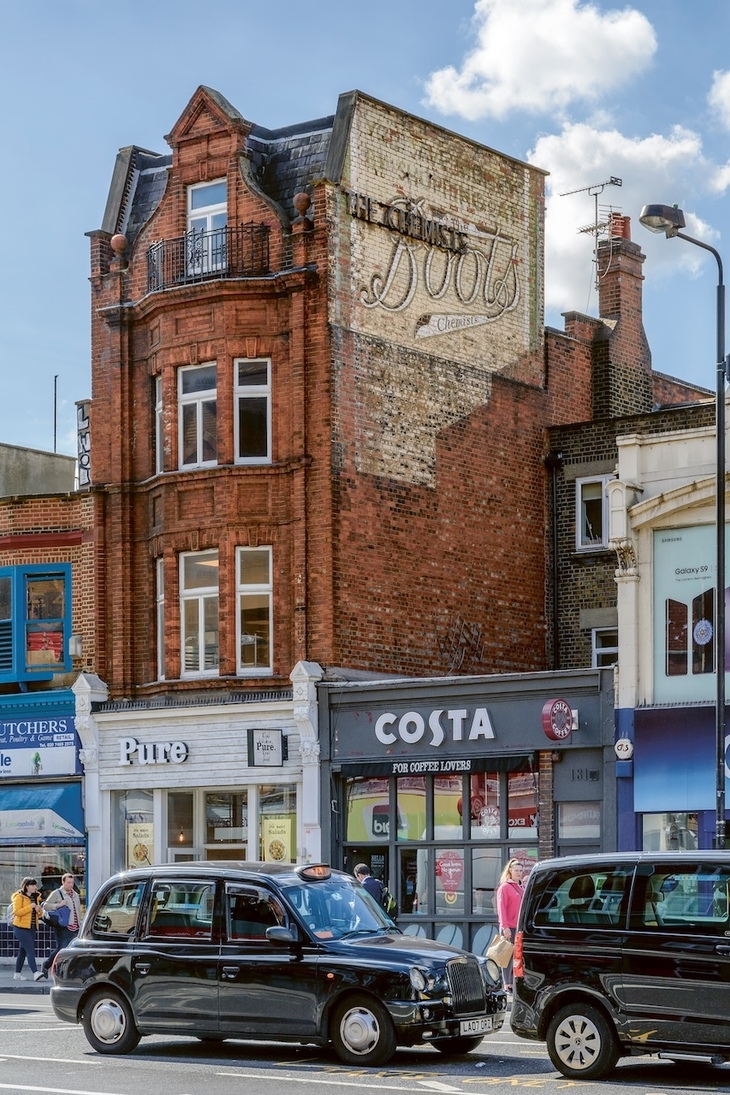 A taxi in front of the Boots ghost sign