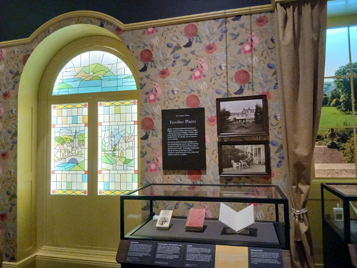 An exhibition room designed to look like the interior of a house, with patterned wallpaper