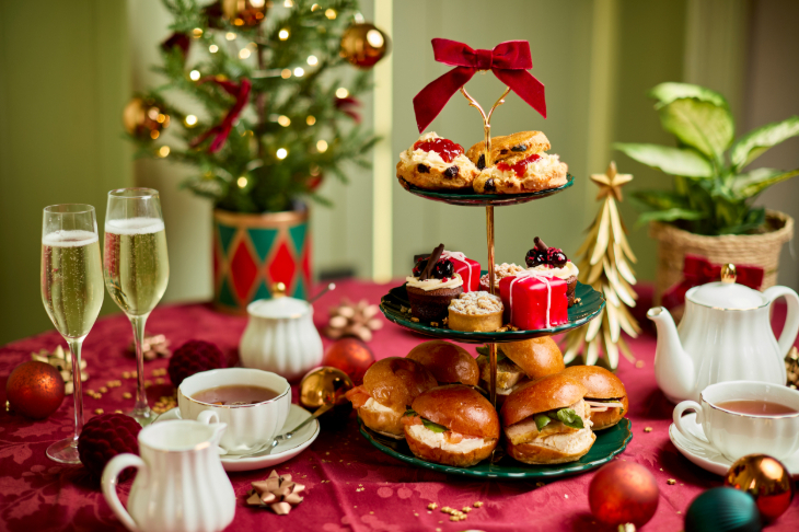 Best Christmas afternoon tea in London 2026: a three-tiered stand decorated for Christmas with a red bow, surrounded by Christmas decorations