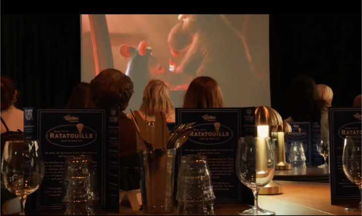Christmas 2026 film screenings in London:  people sitting at tables with wine glasses, watching a film on a large screen