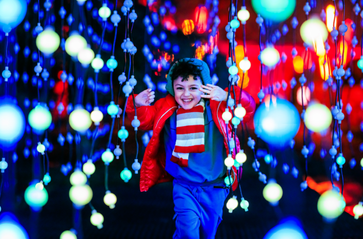 Christmas 2026 in London calendar: a young child running through hanging strings of colourful lights at Christmas at Kew