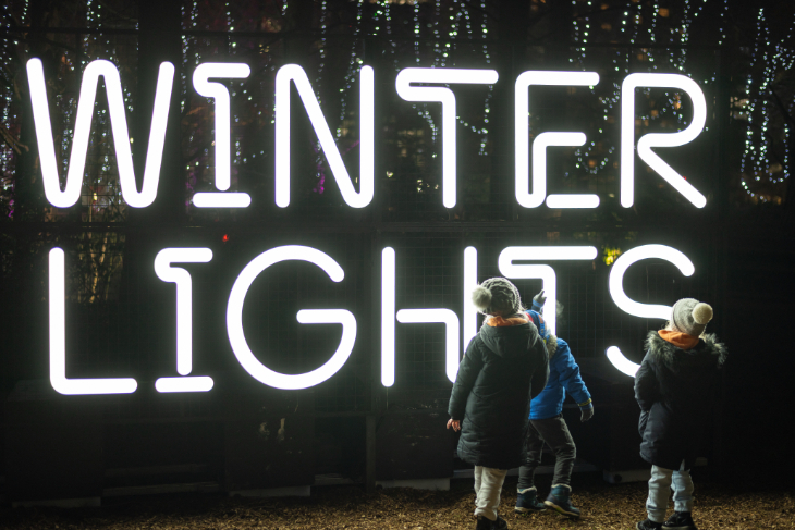 Christmas 2026 best light trails London: children playing in front of a large illuminated 'Winter Lights' sign