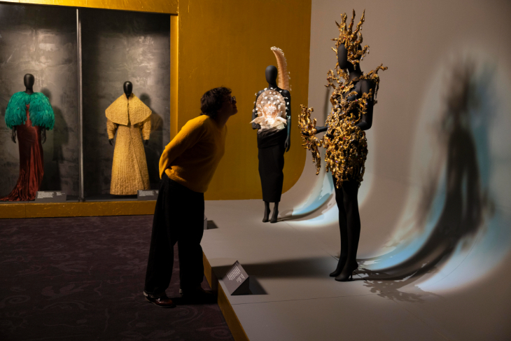 Things to do in London in November 2026: a person leaning in for a closer look at a dress on a mannequin at a fashion exhibition