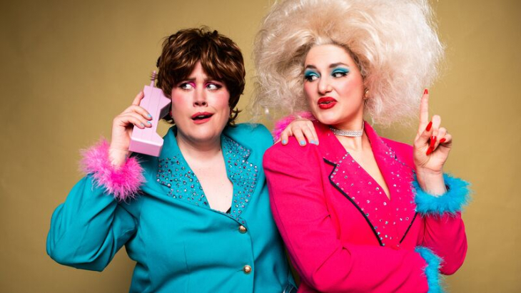 Things to do in London in November 2026:  two people, one in a bright pink suit and one in a bright blue suit, leaning on each other