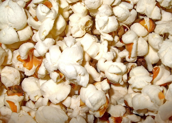 A close-up, overhead view of a pile of white, fluffy popcorn kernels.