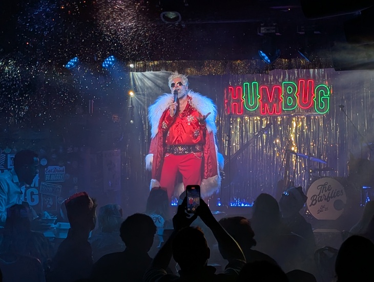 A suave Santa singing on stage