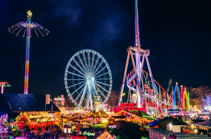 Things to do in London in November 2026: rollercoasters and rides illuminated in the night sky at Hyde Park Winter Wonderland