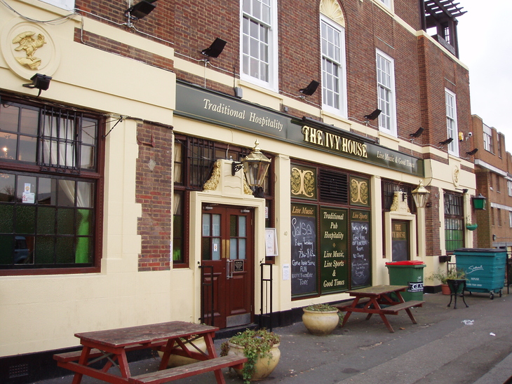 Exterior of The Ivy House pub, a brick and cream building with outdoor picnic tables, green signage, and chalkboard menus.