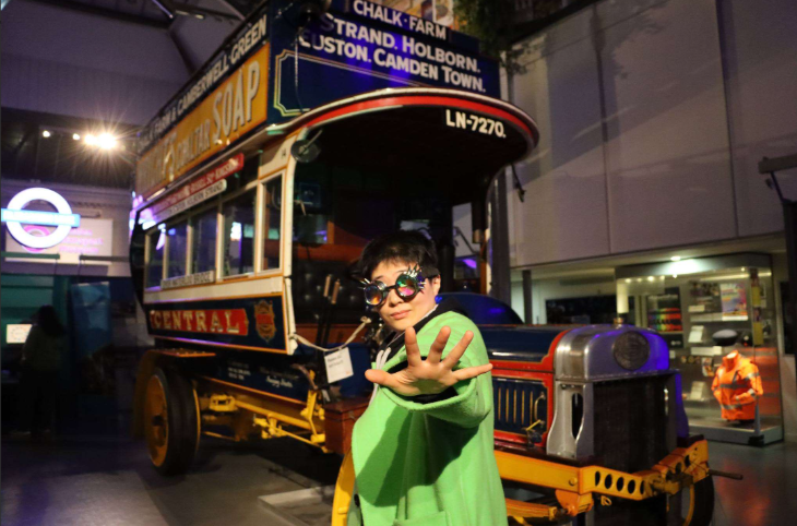 Things to do in London this weekend: a woman wearing novelty glasses in front of  a vintage bus at the London Transport Museum