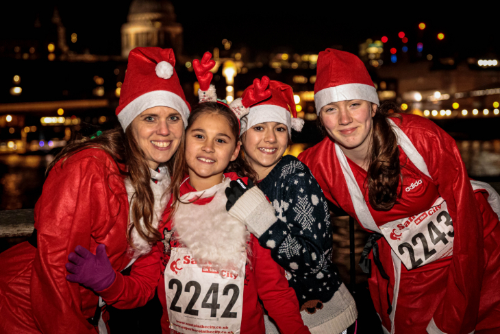 Christmas 2026 volunteering in London: four people dressed as Santa posing for a photo in front of the Thames at night