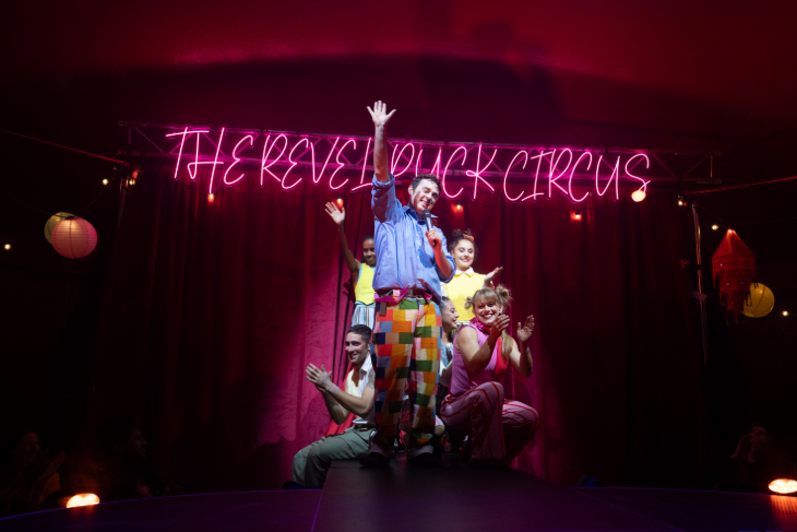 Things to do in London in December 2026: five performers on stage in front of a neon pink "Revel Puck Circus" sign