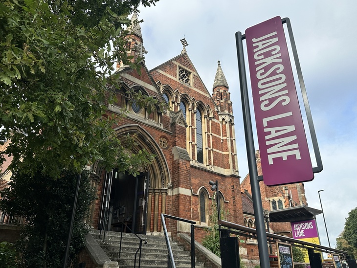 Volunteering in London at Christmas 2026: A red brick Gothic-style church building, now the Jacksons Lane arts centre, with a tall purple sign in the foreground.
