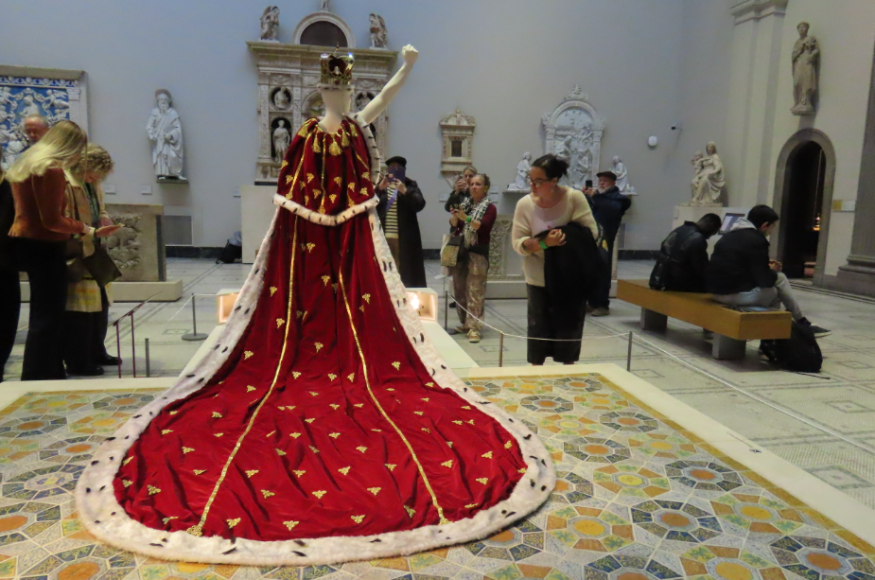A mannequin wearing a long red regal robe and a crown