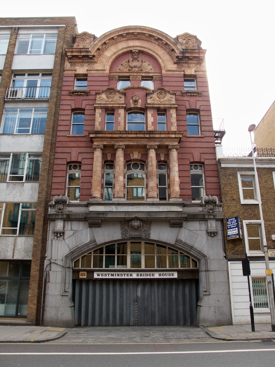 The ornate red brick and stone facade of Westminster Bridge House, featuring a large arched entrance with a grey metal shutter at street level.