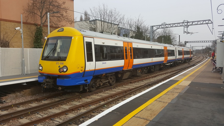A London Overground Class 172 train, numbered 172 008, stopped at a station platform on a cloudy day.